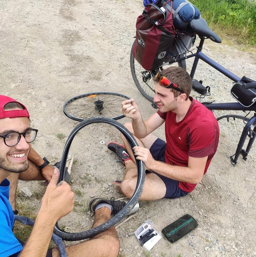Etienne répare son vélo avec l'aide d'un autre homme