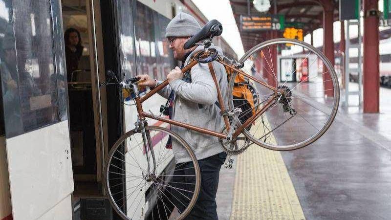 Homme portant son vélo sur l'épaule pour monter dans le train
